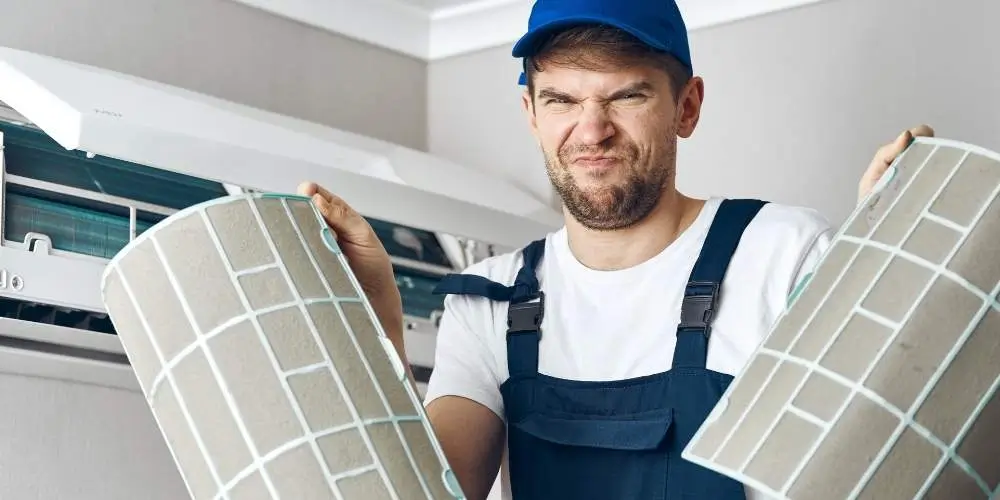 Which Is The Better Option: Having A Dirty Air Filter Or No Air Filter? 1 Dirty Air Conditioner Filter Replacement Dirty air conditioner filter removed for replacement to maintain AC efficiency and air quality.